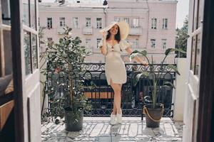 Full length of happy young woman in elegant hat relaxing on the balcony photo