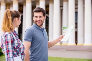 Follow me Happy young tourist couple walking near beautiful building while man holding map photo