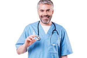 Time for your injection Confident mature doctor holding syringe and smiling while standing isolated on white photo