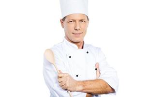 cocinero confiado. chef maduro confiado en uniforme blanco con los brazos cruzados y sonriendo mientras está de pie contra el fondo blanco foto