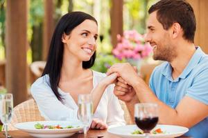 te amo hermosa joven pareja amorosa tomándose de la mano y mirándose mientras se relaja en un restaurante al aire libre juntos foto