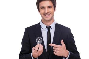 Need some fresh ideas Handsome young man in formalwear holding light bulb and pointing it while standing isolated on white background photo