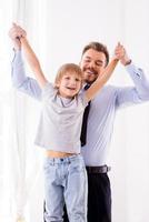 nos encanta pasar tiempo juntos padre feliz en ropa formal divirtiéndose con su hijo en casa foto