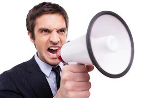 Everybody listen to me Angry young African man in formalwear shouting at megaphone while standing isolated on white background photo