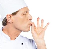 This meal is just perfect Side view of confident mature chef in white uniform keeping eyes closed and gesturing while standing against white background photo