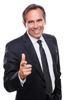 I choose you Confident mature man in formalwear looking at camera and pointing you with smile while standing against white background photo