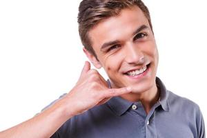 Call me Happy young man gesturing mobile phone near face and smiling while standing isolated on white background photo