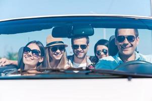 We always travel together Group of young happy people enjoying road trip in their white convertible photo