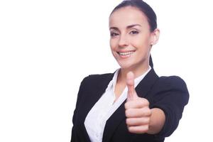 Well done Beautiful young woman in formalwear showing her thumb up and smiling while standing isolated on white photo