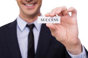 Success Close-up of young man in shirt and tie holding paper with success printed on it while standing isolated on white background photo