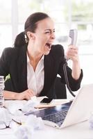 I want that report now Furious young businesswoman in formalwear shouting at the telephone while sitting at her working place photo