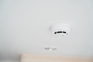 Smoke sensor detector mounted on roof in home or apartment. Safety and conflagration security concept photo