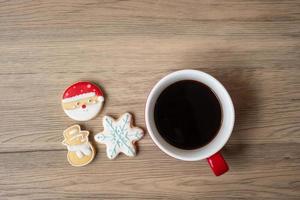 feliz navidad con galletas caseras y taza de café sobre fondo de mesa de madera. concepto de víspera de navidad, fiesta, vacaciones y feliz año nuevo foto