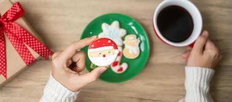 Merry Christmas with woman hand holding coffee cup and homemade cookie on table. Xmas eve, party, holiday and happy New Year concept photo