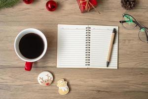 Blank notebook, black coffee cup, Christmas cookies and pen on wood table, Top view and copy space. Xmas, Happy New Year, Goals, Resolution, To do list, Strategy and Plan concept photo
