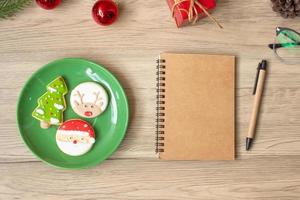 Blank notebook, black, Christmas cookies and pen on wood table, Top view and copy space. Xmas, Happy New Year, Goals, Resolution, To do list, Strategy and Plan concept photo