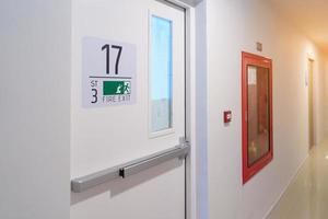 Fire extinguisher system on the wall with Fire Exit door sign for emergency. Stairwell fire for escape in building or apartment photo