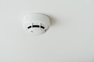 Smoke sensor detector mounted on roof in home or apartment. Safety and conflagration security concept photo