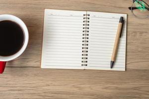 Blank notebook, black coffee cup and pen on wood table, Top view and copy space. Happy New Year, Goals, Resolution, To do list, Strategy and Plan concept photo