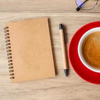 cuaderno en blanco y taza de café en la mesa de madera. motivación, resolución, lista de tareas, estrategia y concepto de plan foto