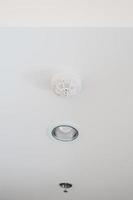 Smoke sensor detector mounted on roof in home or apartment. Safety and conflagration security concept photo