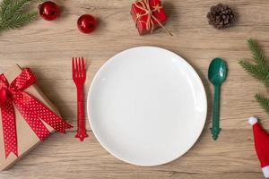 feliz navidad con plato, tenedor y cuchara sobre fondo de mesa de madera. concepto de navidad, fiesta y feliz año nuevo foto