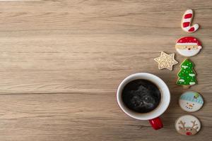 feliz navidad con galletas caseras y taza de café sobre fondo de mesa de madera. concepto de víspera de navidad, fiesta, vacaciones y feliz año nuevo foto