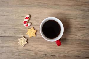 feliz navidad con galletas caseras y taza de café sobre fondo de mesa de madera. concepto de víspera de navidad, fiesta, vacaciones y feliz año nuevo foto