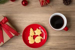 feliz navidad con galletas caseras y taza de café sobre fondo de mesa de madera. concepto de víspera de navidad, fiesta, vacaciones y feliz año nuevo foto