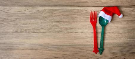 Merry Christmas with miniature Santa Claus, fork and spoon on wood table background. Xmas, party and happy New Year concept photo