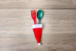 Merry Christmas with miniature Santa Claus, fork and spoon on wood table background. Xmas, party and happy New Year concept photo