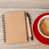 cuaderno en blanco y taza de café en la mesa de madera. motivación, resolución, lista de tareas, estrategia y concepto de plan foto