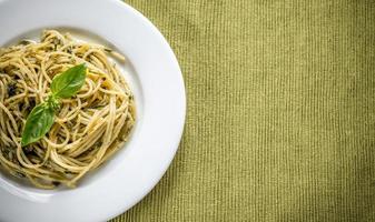 Portion of pasta with pesto sauce and basil leaf photo