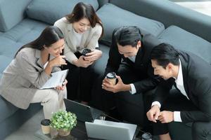 jóvenes empresarios en asia toman un descanso para relajarse en la sala de relajación después de una reunión. viendo películas, tomando fotos, hablando foto