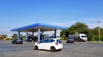 Phitsanulok, Thailand- December 5, 2020 White car, black car and oil transport truck in Thai oil gas station with green tree and blue sky background. Building dessig and Transport with energy concept photo