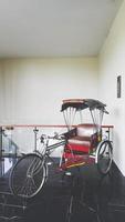 Retro tricycle bike in Thai style or rickshaw parked and show for customer in hotel with wall background in vintage tone. Asian vehicle and Type of bicycle for pick up passengers and tourist to sights photo