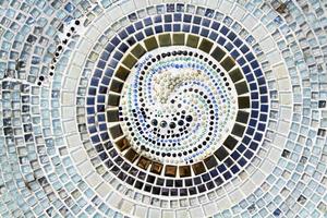colorido del suelo de baldosas de mosaico para el fondo. papel tapiz de diseño de arte, agrietado, forma o círculo o redondo y abstracto. fragmentos de azulejos azules, grises o grises, negros, blancos y marrones y azules en la pared.