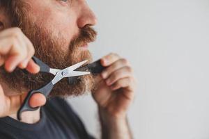Man cutting moustache and beard himself at home photo