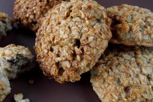 Whole and crushed handmade oatmeal cookies on a brown background. View from above . photo