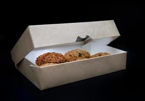 Homemade oatmeal cookies are in an ajar cardboard box. photo