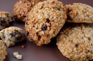 Whole and crushed handmade oatmeal cookies on a brown background. View from above . photo