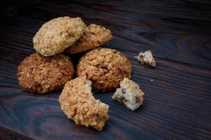 Whole and crushed oatmeal cookies lie on a wooden surface. Rustic oatmeal cookies. photo