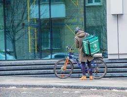 dnepropetrovsk, ucrania - 02.07.2022 un mensajero de servicio de entrega con una bolsa térmica en bicicleta recorre la ciudad. entrega de comida a domicilio. foto