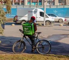 Dnepropetrovsk, Ukraine - 02.09.2022 A delivery service courier with a thermal bag on a bicycle rides around the city. Home food delivery. photo