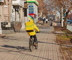 Dnepropetrovsk, Ukraine - 02.09.2022 A delivery service courier with a thermal bag on a bicycle rides around the city. Home food delivery. photo