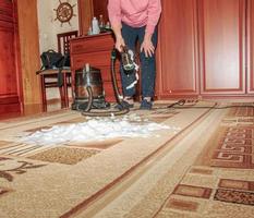 The process of cleaning the carpet with a vacuum cleaner with a water filter. A woman applies cleaning foam to a dirty carpet surface photo