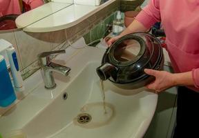 The process of cleaning the carpet with a vacuum cleaner with a water filter. A woman pours dirty water from a vacuum cleaner tank after cleaning photo