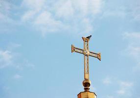 cruz de la iglesia ortodoxa contra el cielo azul. una golondrina se sienta en una cruz. concepto de pascua foto