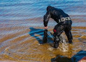 Professional diver near the river coastline. Commercial diving. photo