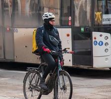 Dnepropetrovsk, Ukraine - 02.09.2022 A delivery service courier with a thermal bag on a bicycle rides around the city. Home food delivery. photo